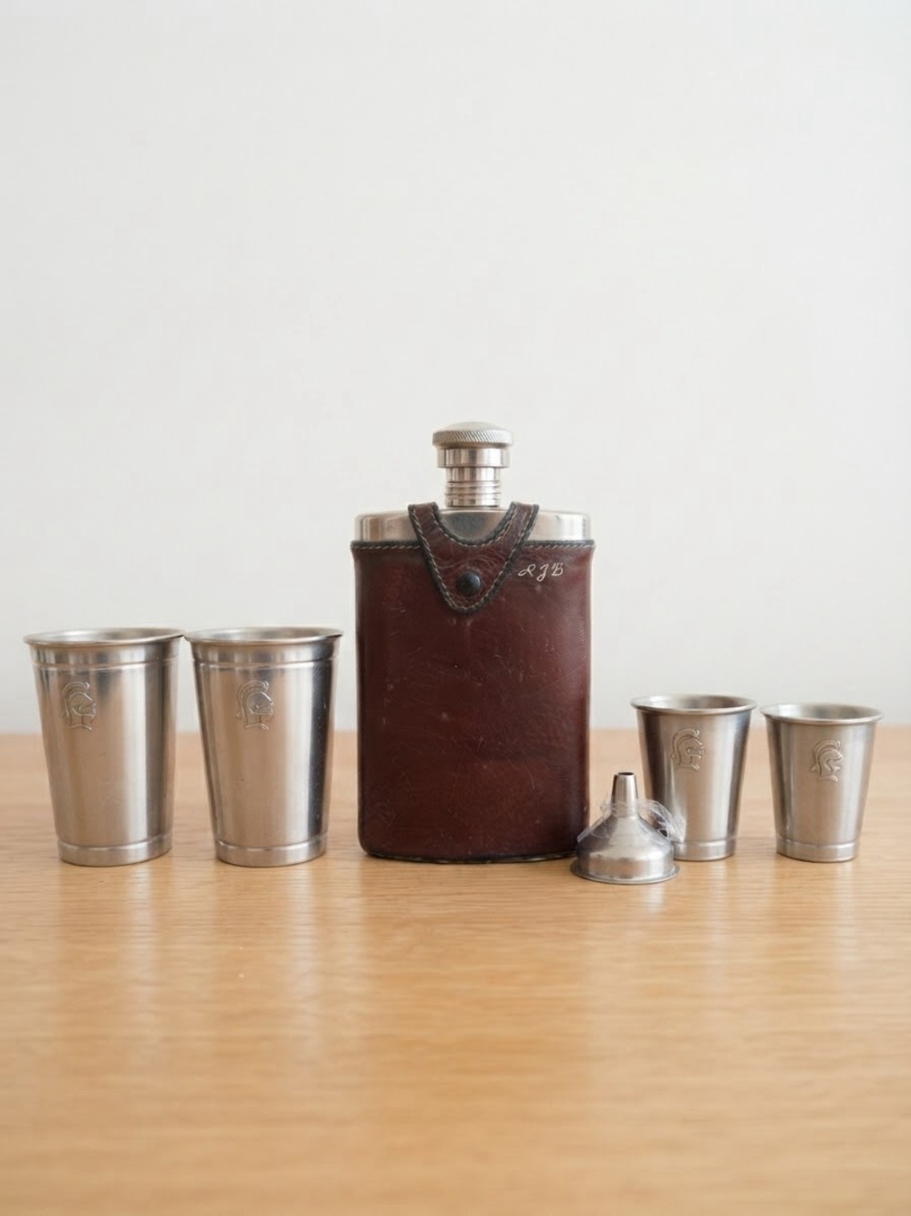 Set containing a leather-trimmed flask, four metal shot glasses, and a funnel.